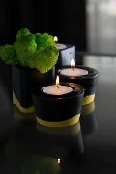 candles and moss in black and yellow concrete candle holders.