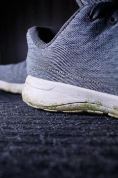 Gray men's sneakers with a dirty sole from the earth and grass, shoes for jogging and sports