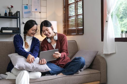 Asian beautiful lesbian women couple hugging girlfriend in living room. Attractive two female gay friend sitting on sofa in living room, feel happy and enjoy spending time together on holiday in house.