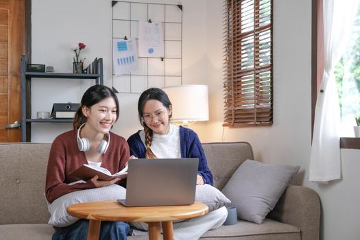 Two asian students learning together online with a laptop and tutor together at home..