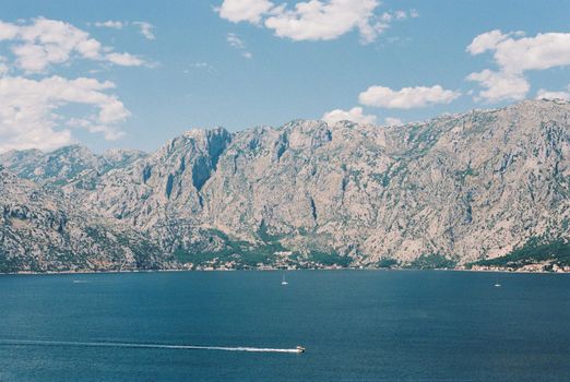 Motor boats float on the blue sea against the backdrop of a high mountain range. High quality photo