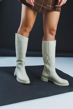 Luxury elegant white women's leather flat sole boots on women's feet. Collection of winter women's leather shoes