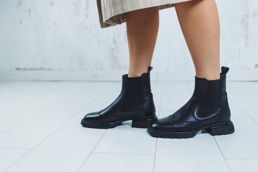 Close up of female legs in black leather Chelsea boots. New autumn collection of women's leather shoes 2022