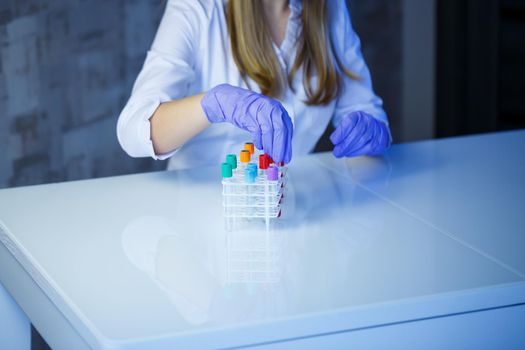 A medical professional, laboratory assistant, doctor performs an analysis in a laboratory, uses test tubes, a pipette and a petri dish for the presence of bacteria in the human body