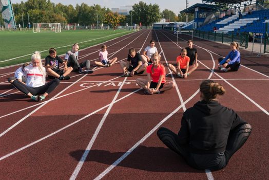 Female coach and group of children conducts a training session at the stadium. School gym trainings or athletics