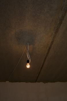 Light bulb on the ceiling. Lonely light bulb and wire sticking out of the ceiling during a repair