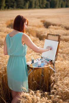 Warm summer time, female painter makes a piece of art, using oil paints