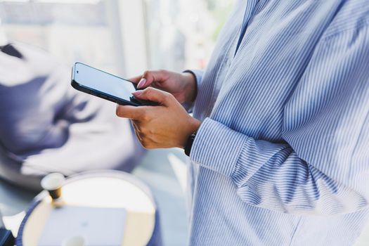 A modern mobile phone with a black screen is held in the hands of a woman, female hands with a smartphone close-up