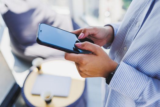 A modern mobile phone with a black screen is held in the hands of a woman, female hands with a smartphone close-up