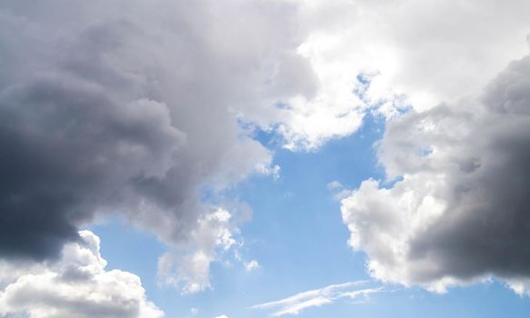 Summer sky. Cumulus clouds on a blue background. Partly cloudy. Dark clouds and white clouds.