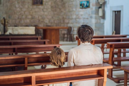 Christian dad tells his son Bible stories about Jesus sitting in kirk. Faith, religious education, modern church, father day, fatherly responsibilities, father influence on formation of son worldview.