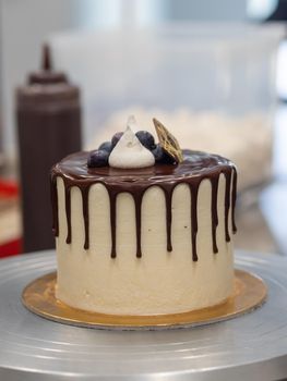 unrecognizable worker preparing a sweet dripping choco cake and berries