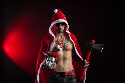 the man in a red Santa Claus Cape with an axe and a metal bull figurine symbol of the new year 2021