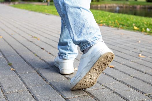 A woman walks on the sidewalk, close-up of legs