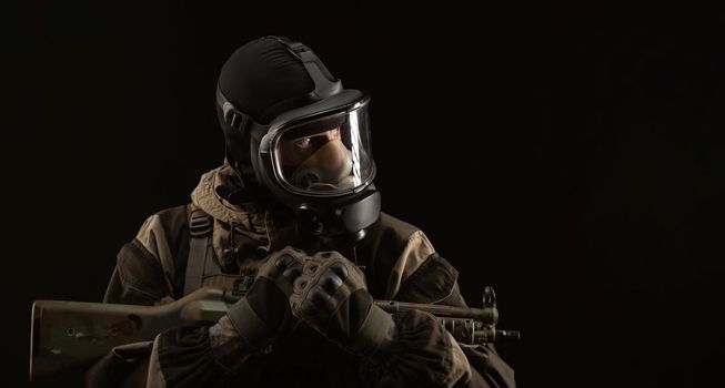 man in a military uniform and a gas mask holds a weapon with an angry expression of emotion