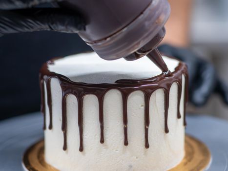unrecognizable worker preparing a sweet dripping choco cake and berries