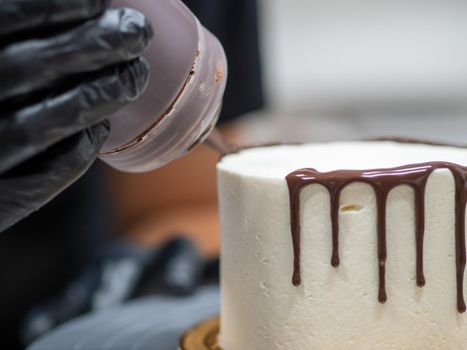 unrecognizable worker preparing a sweet dripping choco cake and berries