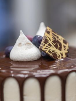 unrecognizable worker preparing a sweet dripping choco cake and berries