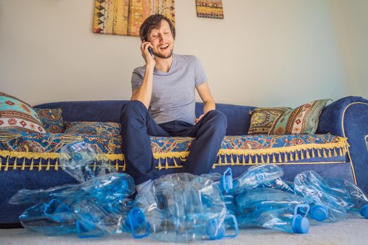 Young caucasian man hamong empty plastic bottles to recycle with sad expression.