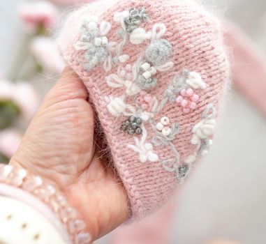 Pink handmade knitted hat for newborn studio photoshoot decorated with flowers. Infant accessory woolen wear