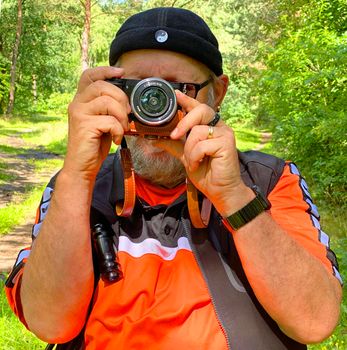 Male photographer with compact camera photographing towards the viewer