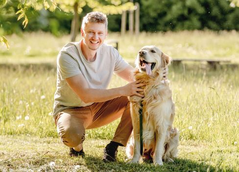 Man walking golden retriever on leash in nature