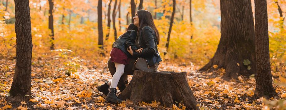 Mother and daughter spend time together in autumn yellow park. Season and single parent
