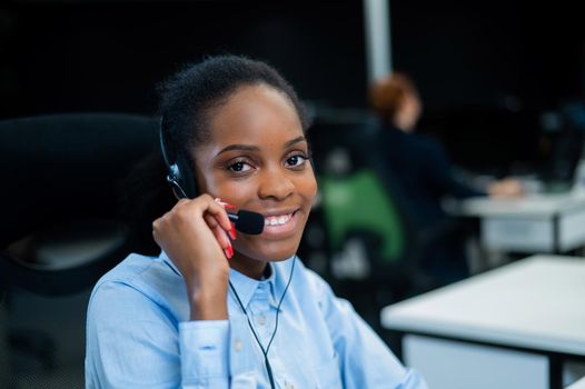 African young woman talking to a client on a headset. Female employee of the call center