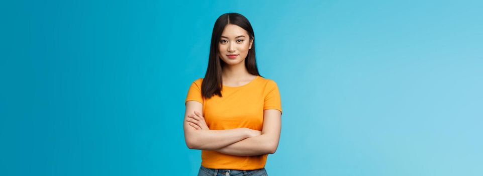 Confident motivated feminine asian woman feel empowered deal office problems manage business, hold hands crossed chest, smiling determined, wear yellow t-shirt, stand blue background.