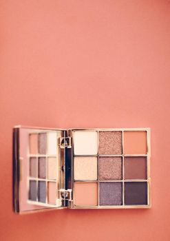 Cosmetic branding, mua and girly concept - Eyeshadow palette and make-up brush on orange background, eye shadows cosmetics product as luxury beauty brand promotion and holiday fashion blog design