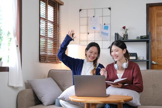 Two asian students learning together online with a laptop and tutor together at home..