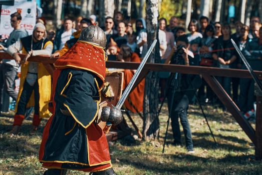 A warrior in red and black robes and a helmet. Festival of medieval culture. Imitation of jousting tournaments. Arena with spectators. Bishkek, Kyrgyzstan - October 13, 2019