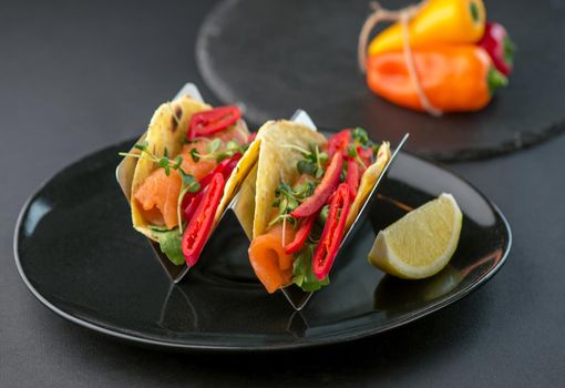 Spicy tacos with tomatoes and meat on a dark background