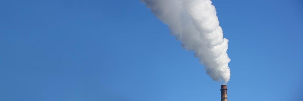 Chimney blows white smoke into blue sky. Air pollution from an industrial chimney