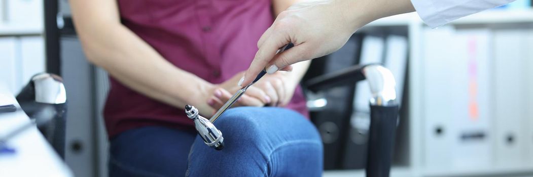 Neurologist examines patient and taps leg with hammer. Pathological reflexes concept