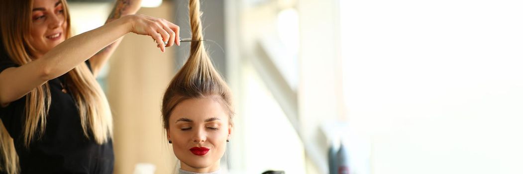 Woman hairdresser holds a client ponytail and scissors. Beauty salon services and trendy haircuts concept