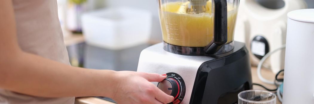 Woman cook turning on button of food processor for kneading dough closeup. Household appliances as assistant in cooking concept