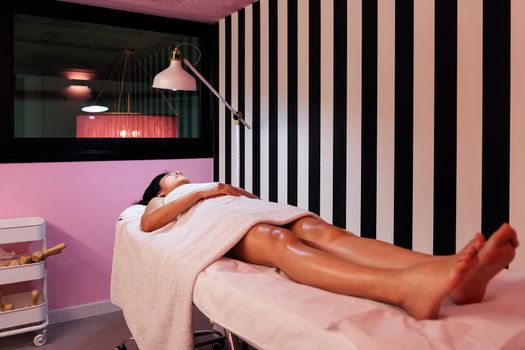 unrecognizable young woman resting lying on the beauty salon couch after a relaxing massage, concept of body care and wellness