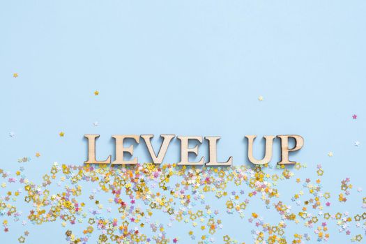 Level up wooden inscription on a colored background with stars. Achievement concept.