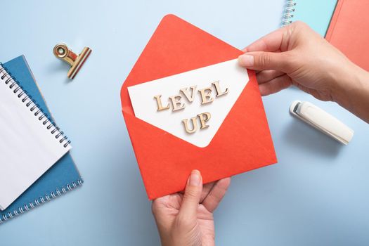Level up inscription in the red envelope in female hands. Business and achievement concept.