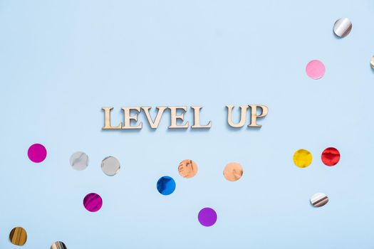 Level up wooden inscription on a colored background with tinsel. Achievement concept.