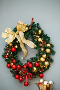 Christmas wreath with branches of a Christmas tree hanging on the wall. New Year's decor in a cozy home