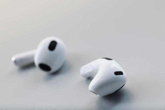 White wireless bluetooth earbuds on a gray background. Fashion phone accessory, headphone noise reduction