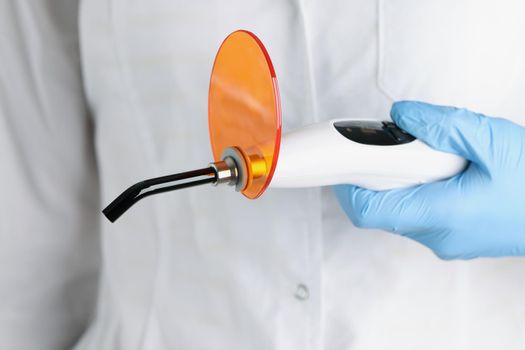 The doctor is holding dental curing light, close-up. Instruments for prosthetics fillings, solidify the teeth whitening material