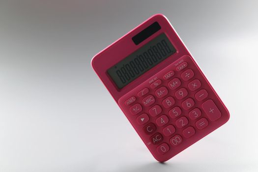 Red calculator on a gray background, close-up. The concept of cash accounting, costing, goods inventory