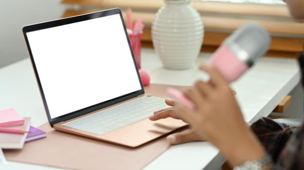 Close up view of man using laptop and microphone streaming audio podcast. Entertainment, podcasts and technology concept.