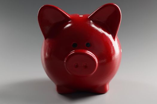 In the center is a red ceramic piggy bank on a gray background, close-up. Retirement savings, bank deposit
