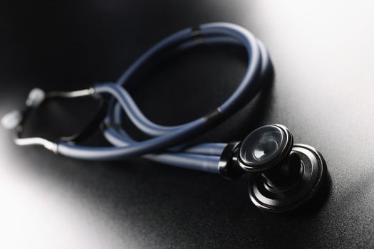 Black medical stethoscope on a dark matte background, close-up. Design element,texture. Therapist's medical tool