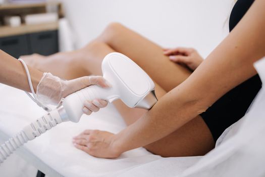 Cosmetology. Beautiful woman receiving laser hair removal procedure at beauty salon. Beautician doing beauty treatment for female arm at spa salon.