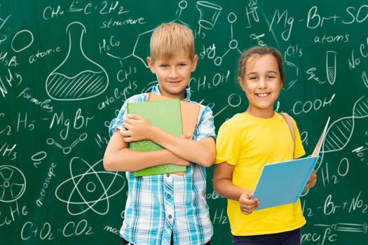 children on the background of formulas, isolated on green wall chalk board background. Childhood children kids education lifestyle concept.
